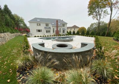 A serene backyard featuring a stone fountain and a grand house surrounded by nature's beauty.